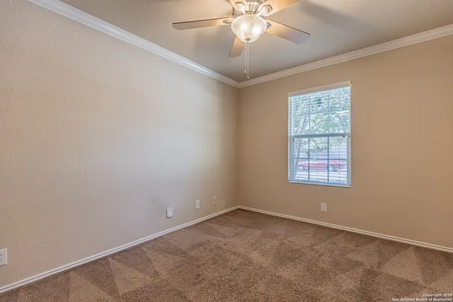 an empty room with a chandelier fan and windows