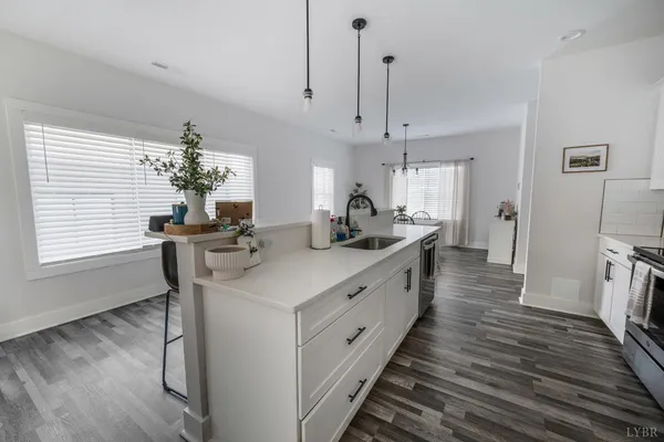a large kitchen with stainless steel appliances a table chairs in it and wooden floors