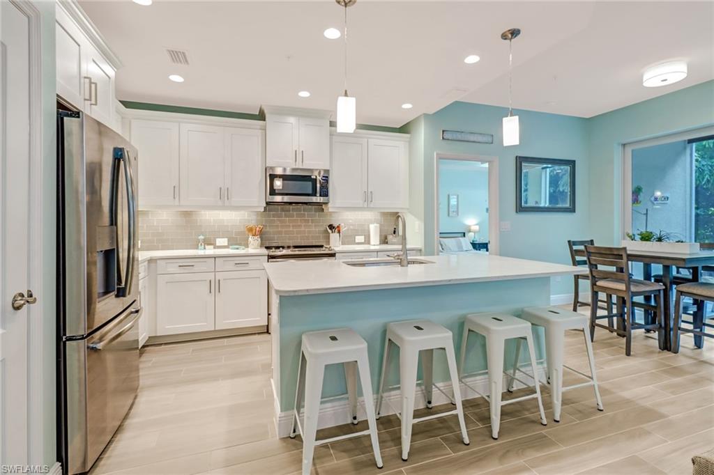6959 Avalon Circle, Unit 1704 Naples, FL 34112 - Photo 3 of 25 a kitchen with white cabinets and stainless steel appliances