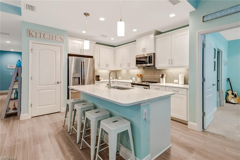 6959 Avalon Circle, Unit 1704 Naples, FL 34112 - Photo 5 of 25 a kitchen with kitchen island granite countertop a sink a stove a refrigerator cabinets and wooden floor