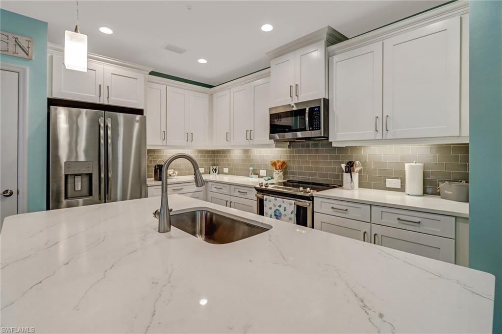6959 Avalon Circle, Unit 1704 Naples, FL 34112 - Photo 6 of 25 a kitchen with stainless steel appliances granite countertop a refrigerator sink and stove