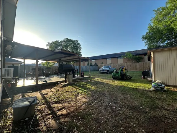 a view of a backyard with table and chairs under an umbrella with wooden fence