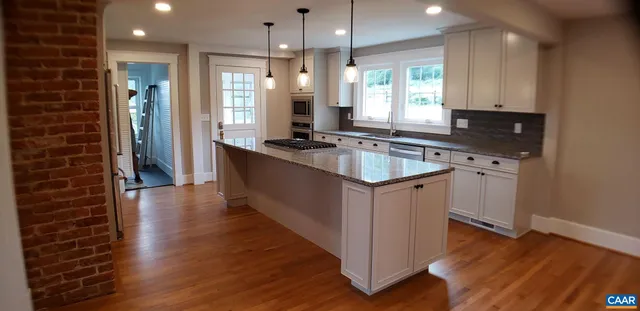 a kitchen with stainless steel appliances granite countertop a sink stove and wooden floor