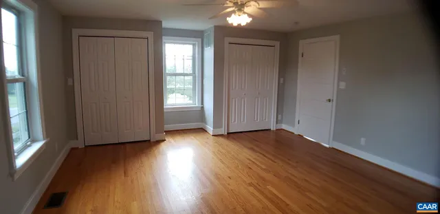 an empty room with wooden floor and windows