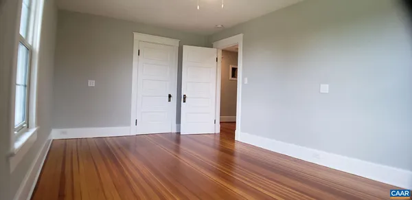 a view of an empty room with wooden floor and a window
