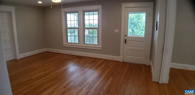 an empty room with wooden floor and windows