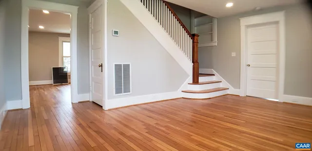 a view of an empty room with wooden floor and stairs