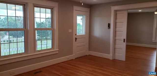 an empty room with wooden floor and windows