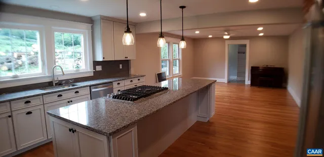 a kitchen with stainless steel appliances granite countertop a sink a stove and a wooden floor