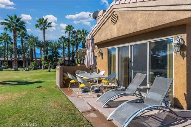 a view of a patio with table and chairs potted plants and palm trees