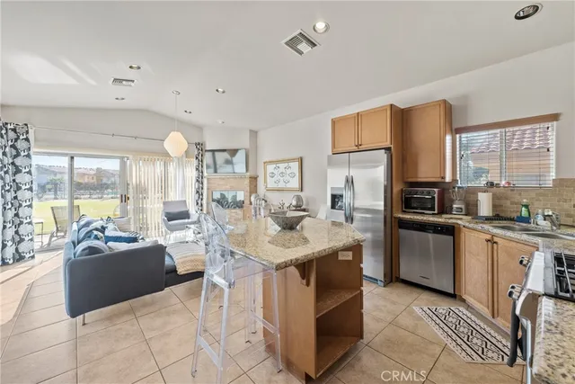 a kitchen with stainless steel appliances granite countertop a stove top oven a sink dishwasher a dining table and chairs with wooden floor