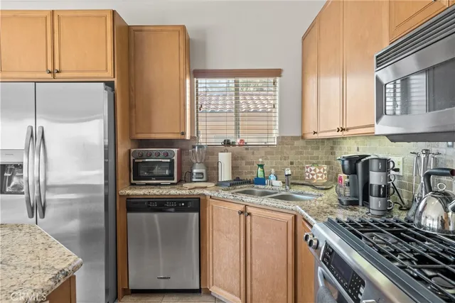 a kitchen with stainless steel appliances granite countertop a stove a sink and a refrigerator