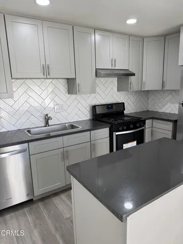 a kitchen with stainless steel appliances granite countertop a sink a stove and a refrigerator