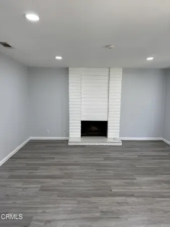 a view of empty room with wooden floor and fireplace