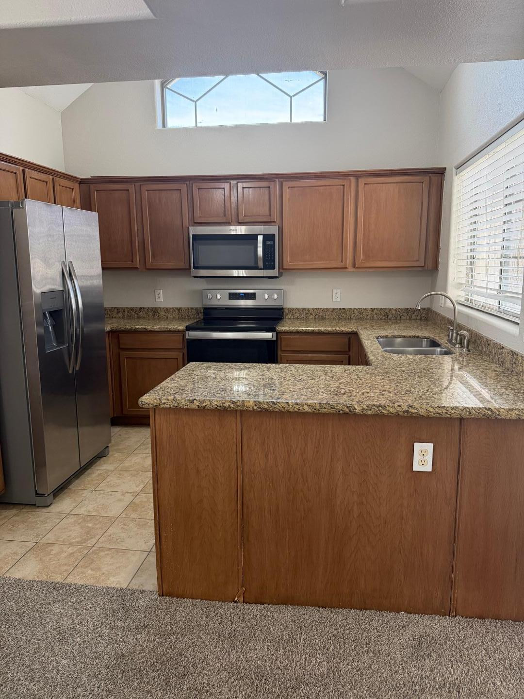 a kitchen with stainless steel appliances granite countertop a stove a sink and a refrigerator