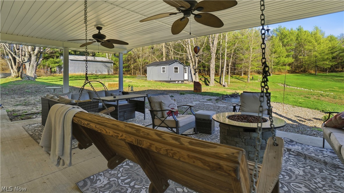 65892 Endley Road Cambridge, OH 43725 - Photo 46 of 50 View of patio with ceiling fan, an outdoor living space with a fire pit, and a storage unit