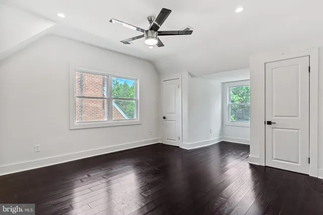 an empty room with wooden floor chandelier fan and windows