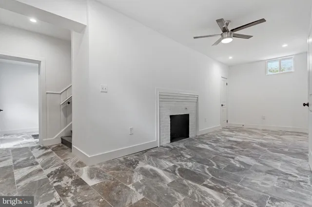 an empty room with fireplace and ceiling fan