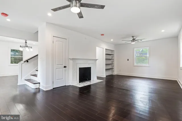 an empty room with wooden floor fireplace and windows