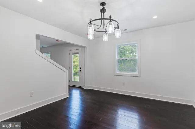 an empty room with wooden floor chandelier and window