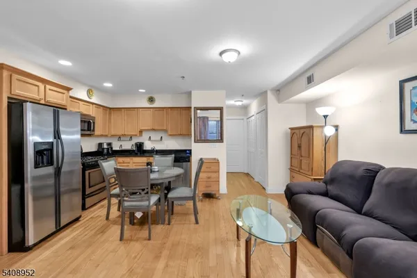a living room with stainless steel appliances kitchen island granite countertop furniture and a refrigerator