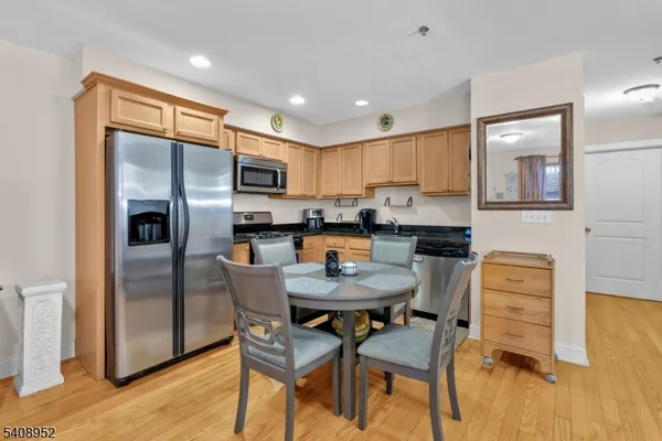 a kitchen with stainless steel appliances kitchen island granite countertop a dining table chairs and a refrigerator