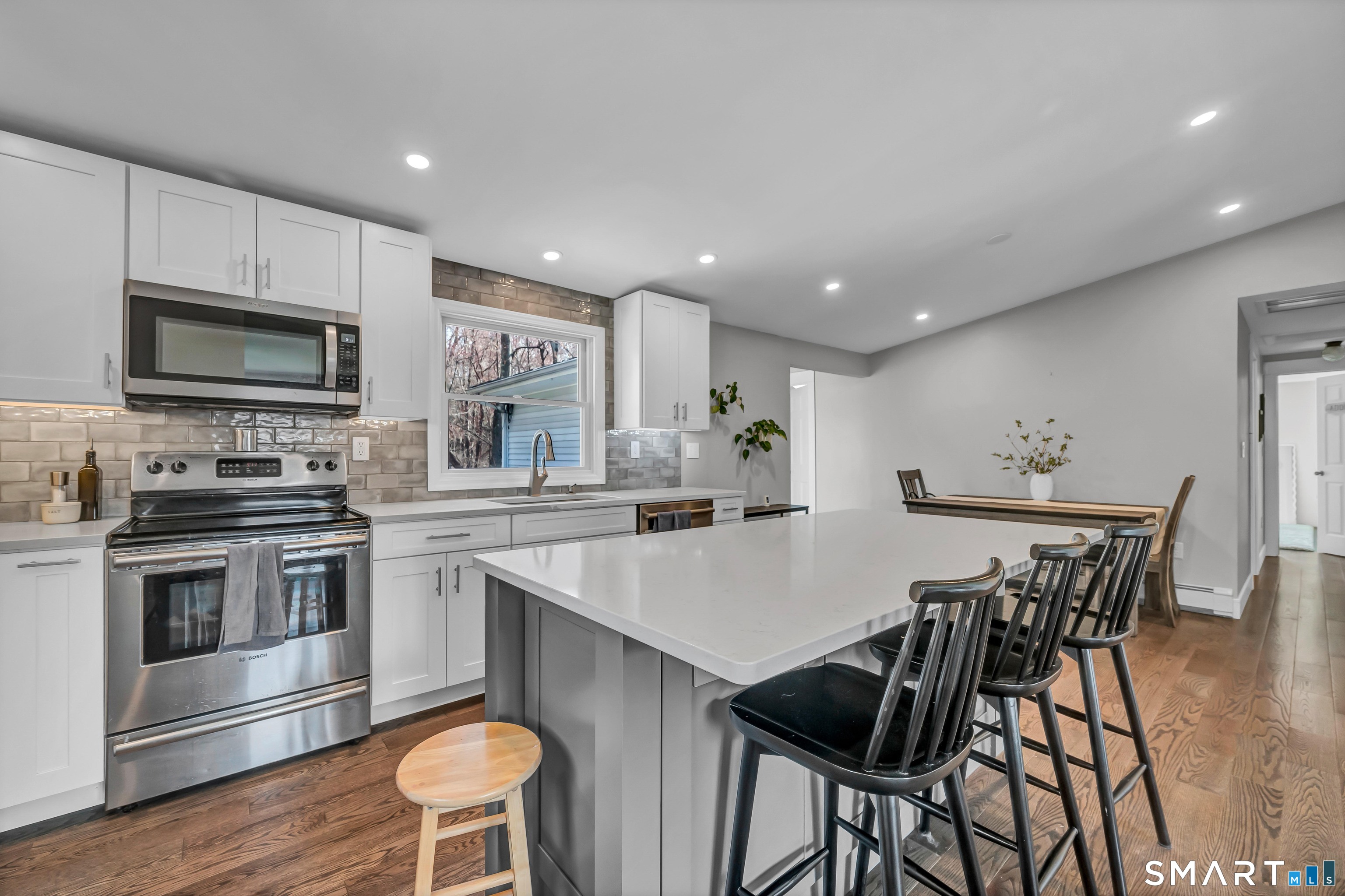 10 Grove Place Bethel, CT 06801 - Photo 5 of 33 a kitchen with stainless steel appliances kitchen island granite countertop a stove a sink a microwave a dining table and chairs with wooden floor