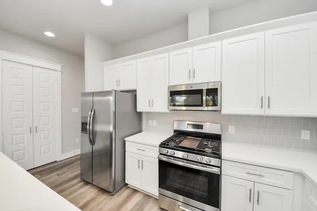 a kitchen with stainless steel appliances white cabinets and a stove top oven