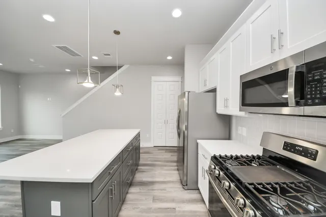 a kitchen with stainless steel appliances a stove a microwave and white cabinets