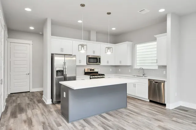 a kitchen with white cabinets and stainless steel appliances