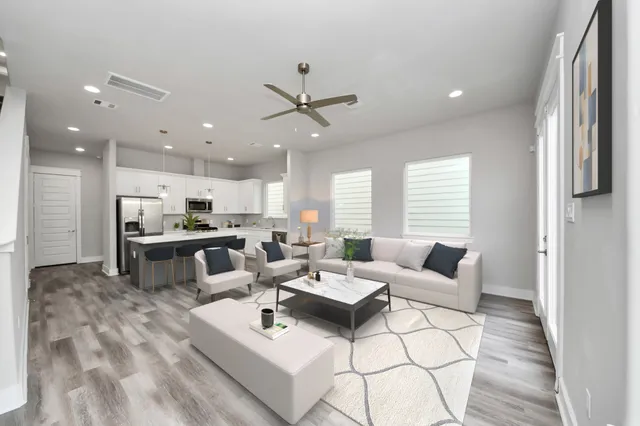 a living room with furniture kitchen view and a large window