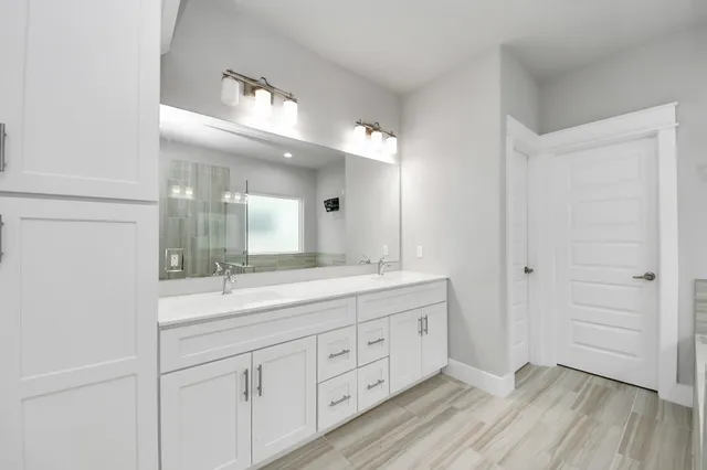 a bathroom with a granite countertop double vanity sink a mirror and a