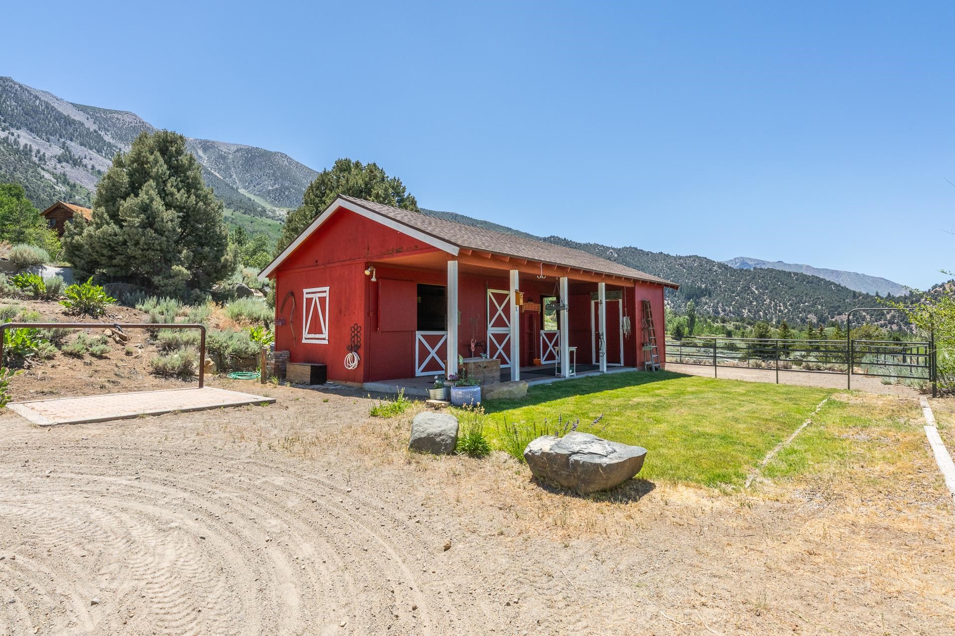 537 Aspen Spring Ranch Road Mammoth Lakes, CA 93546 - Photo 27 of 40 Red barn structure with a covered porch featuring white support columns and white cross-buck door accents