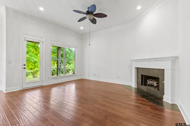 an empty room with wooden floor a ceiling fan and a fireplace