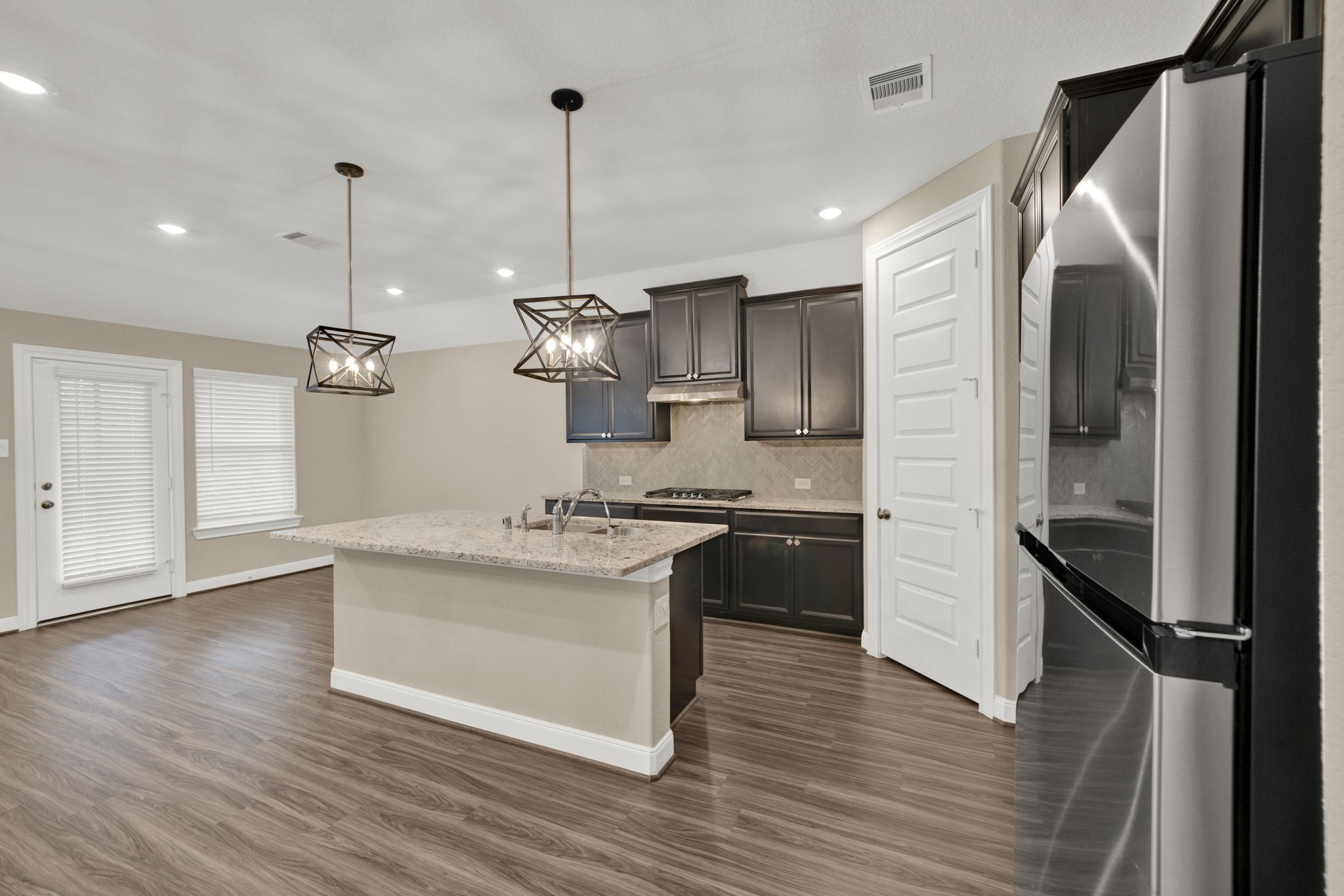 2217 Gadwall Court Conroe, TX 77384 - Photo 5 of 35 a kitchen with stainless steel appliances granite countertop a sink a stove a refrigerator and island with wooden floor
