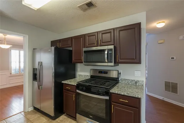 a kitchen with stainless steel appliances granite countertop a stove microwave and refrigerator