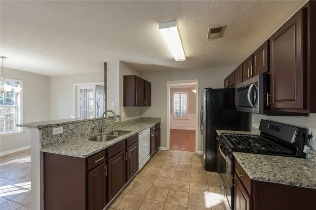 a kitchen with a granite countertop sink stove and refrigerator
