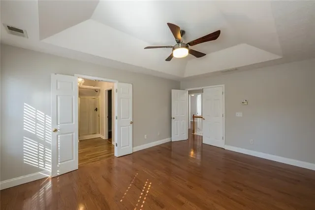 a view of empty room with wooden floor and ceiling fan