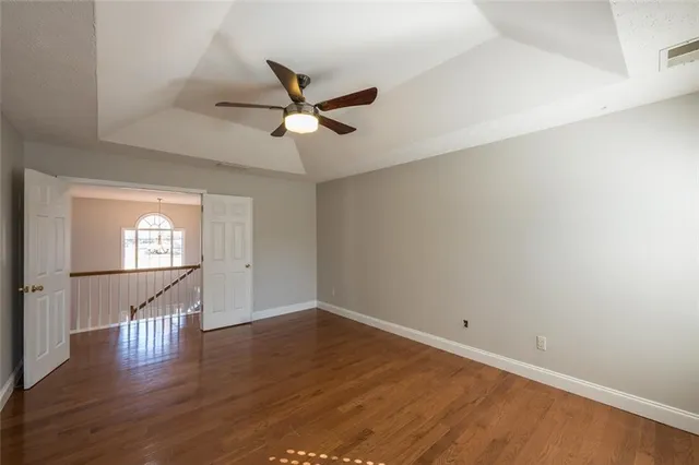 a view of empty room with wooden floor and fan