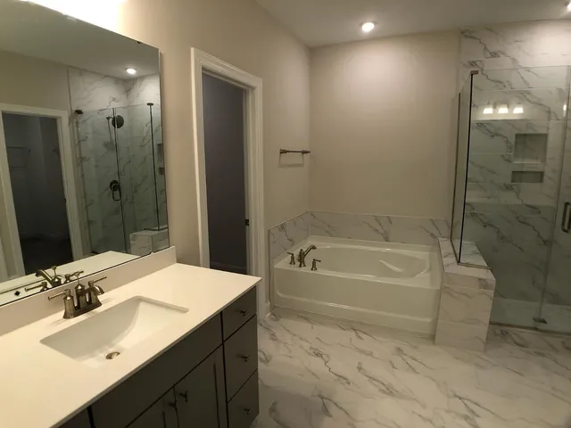 a bathroom with a tub sink double vanity and a mirror