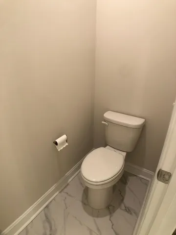 a white toilet sitting next to a white wall