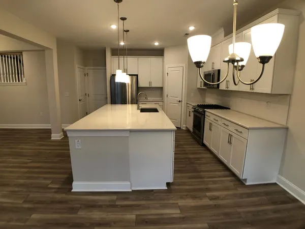 a kitchen with kitchen island a counter top space a sink and appliances