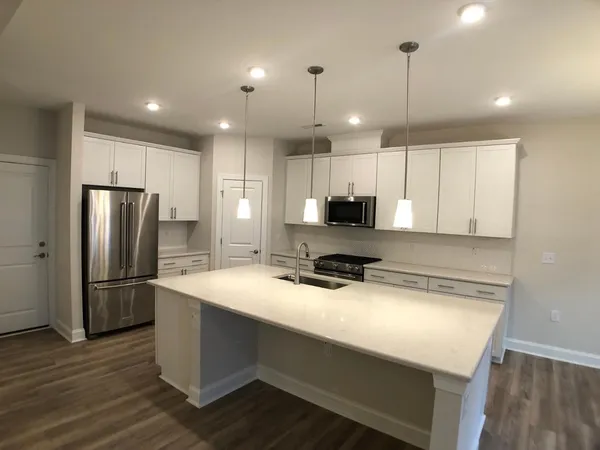 a kitchen with kitchen island a refrigerator a sink and wooden floor