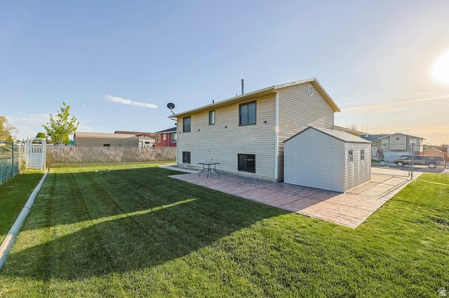 5896 South 3950th Street West Roy, UT 84067 - Photo 2 of 29 Rear view of house with a fenced backyard, a patio area, and a gate