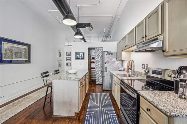 a kitchen with stainless steel appliances granite countertop a stove top oven a refrigerator a sink dishwasher and white cabinets with wooden floor