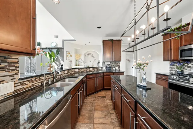 a kitchen with stainless steel appliances granite countertop a sink a stove and a wooden cabinets