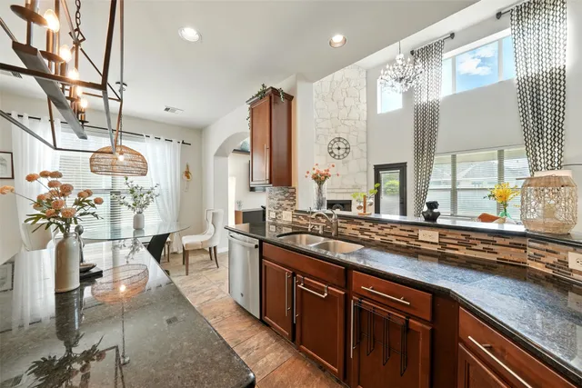 a spacious kitchen with stainless steel appliances granite countertop a sink a stove and a wooden cabinets
