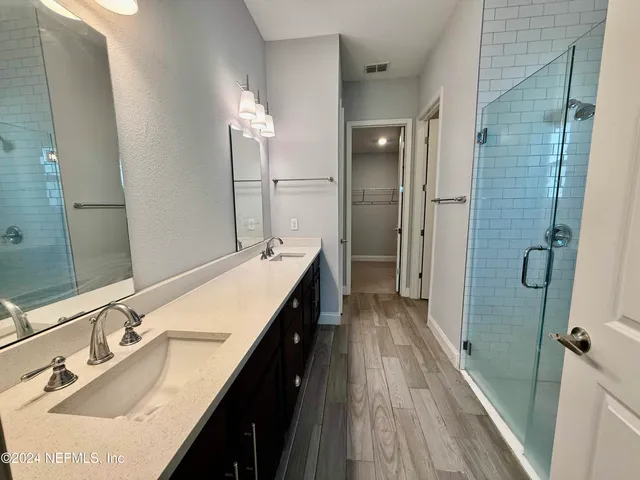 a bathroom with a double vanity sink a mirror and shower