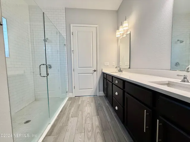 a spacious bathroom with a double vanity sink a large mirror and shower