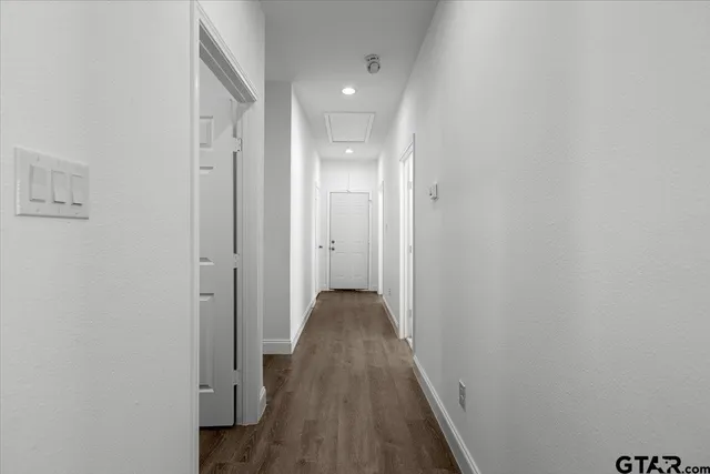 a view of a hallway with wooden floor and a bathroom